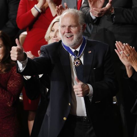 Rush Limbaugh poses for a picture in a black suit.